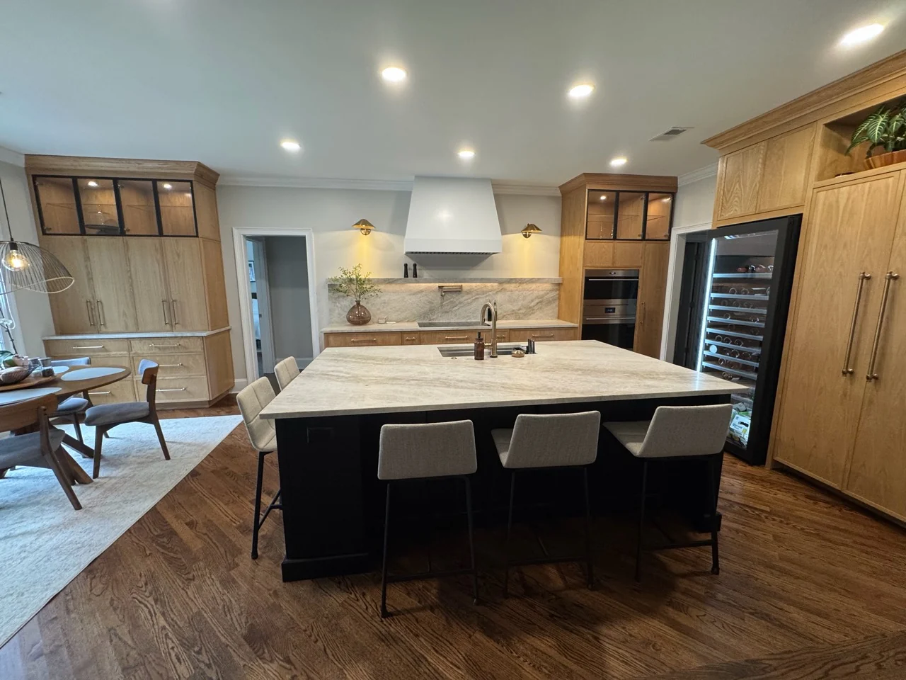 Renovated kitchen with large island, wood cabinetry, stone counters, and black-framed glass cabinet doors