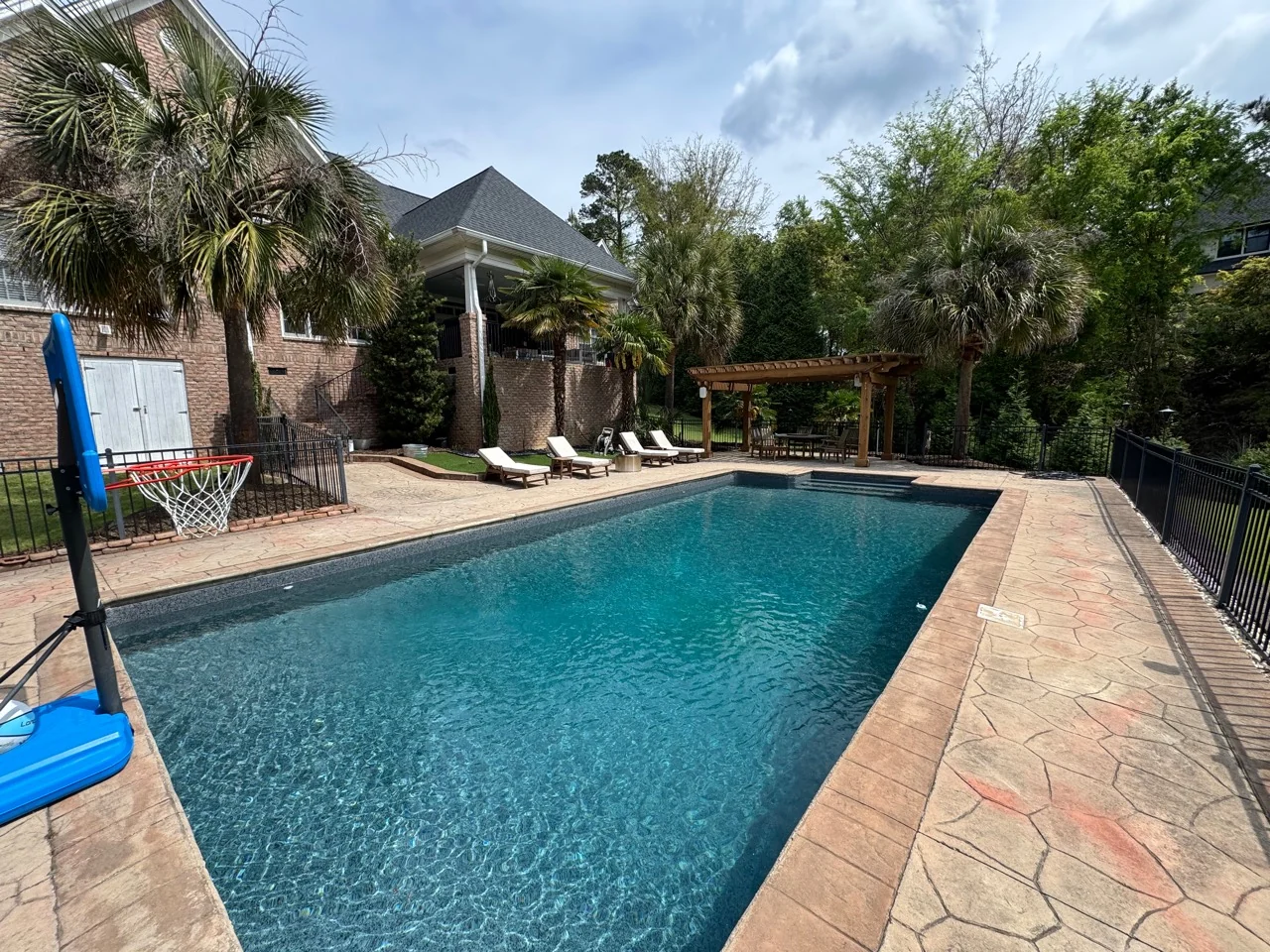 Swimming pool with paved surround, lounge chairs, pergola, and covered porch
